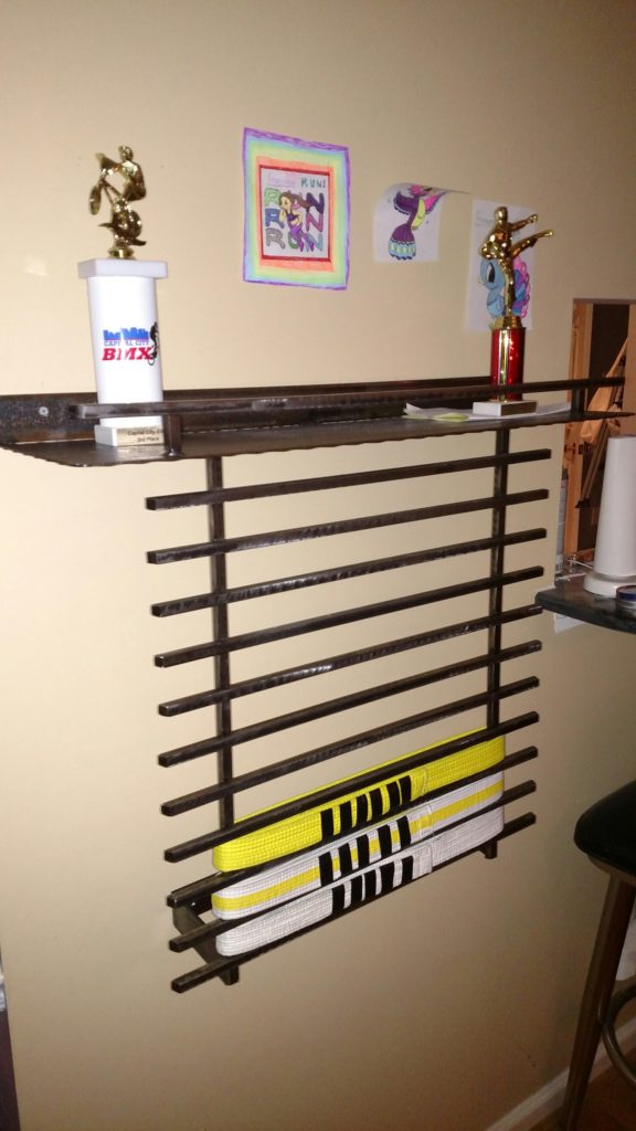 Wall rack with individual holders for taekwondo belts and shelf